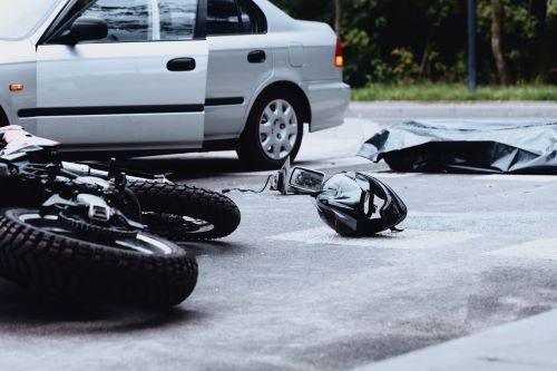 A crash scene between a white car and a motorcycle. 