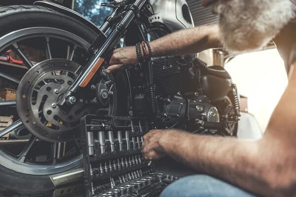 owner performing routine maintenance on his motorcycle