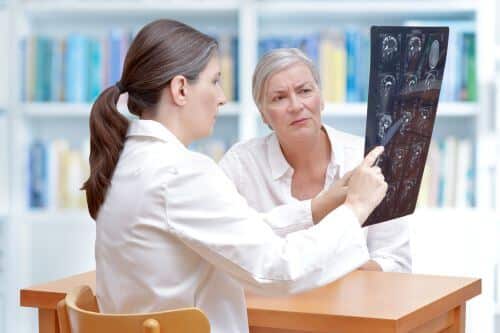 A female doctor reviews head trauma scans with her patient with dementia.