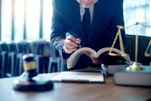 A personal injury lawyer is researching in a law book in his Smithtown office.