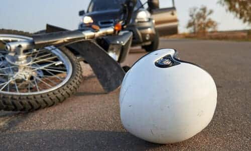 A white helmet in front of a wrecked motorcycle after a rear end accident.