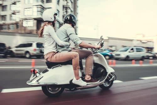 A couple drives through New York City on a moped.