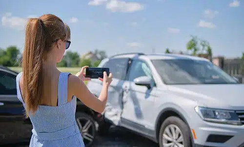 young female taking pictures for evidence in side impact car accident scene